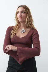 Top de tejido acanalado negro, con escote en V, mangas largas con terminación acampanada y ajuste al cuerpo.