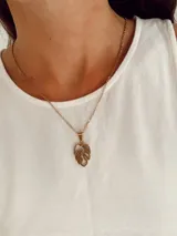 Collar de cadena fina de eslabones con dije colgante en forma de hoja calada, fabricado en acero quirúrgico con acabado dorado.
