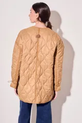 Campera color camel con diseño acolchado, cierre con botones a presión, cuello de piel sintética desmontable, bolsillos delanteros y puños ajustables con lazo.
