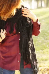 Bufanda triangular tejida en lana merino, de color negro, con diseño calado y terminación de flecos largos en los bordes.