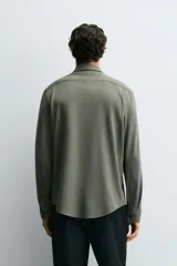 Camisa de corte regular fit color celeste, confeccionada en tejido fácil de planchar. Cuenta con cuello italiano abierto, manga larga con puño abotonado y cierre frontal con botonadura.