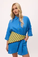 Vestido camisero negro de algodón, con mangas tres cuartos y cuello camisero. Presenta detalles de costura en zigzag color naranja en el cuello y en los puños.