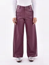 Pantalón de corte ancho y relajado, confeccionado en cuero sintético color borravino. Cuenta con bolsillos frontales aplicados de diseño geométrico, tiro alto y trabillas para cinturón.
