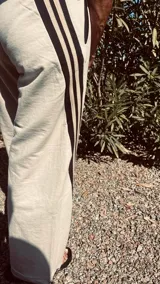 Pantalón deportivo color naranja con las icónicas tres rayas blancas laterales características de la marca Adidas.