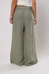Pantalón de lino color verde seco, de corte amplio y relajado, con cintura elástica y detalle de aperturas laterales con botones de nácar en el ruedo.