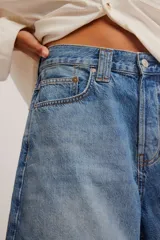 Bermuda de denim rígido azul claro, de tiro medio y calce relajado, con diseño clásico de cinco bolsillos y cierre frontal con botones.
