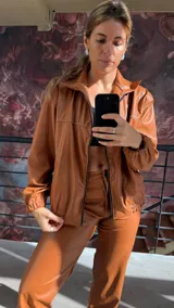 Campera bomber color marrón de cuero sintético con cierre frontal, cuello clásico y puños elásticos.