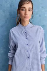 Camisa de rayas blancas y azules con cuello mao decorado con volados sutiles, cierre frontal de botones y mangas largas.