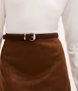 Kit de dos cinturones femeninos de anchura fina, confeccionados en material sintético efecto gamuza. Cuentan con hebilla metálica plateada, trabillas reforzadas y perforaciones para ajuste.