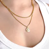 Collar doble dorado con una cadena de eslabones gruesos y otra de eslabones finos, con un dije ovalado texturizado.