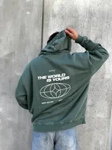 Canguro verde con capucha y cordones ajustables. Presenta un bolsillo tipo canguro y dos estampados blancos: un logo con forma de globo terráqueo en el lado izquierdo del pecho y una flor en el lado derecho.