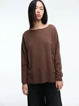 Sweater de punto amplio en viscosa liviana, color marrón, con detalle de micro lentejuelas integradas al tejido. Presenta cuello redondo amplio, hombros caídos y mangas largas con terminación en puño acanalado.
