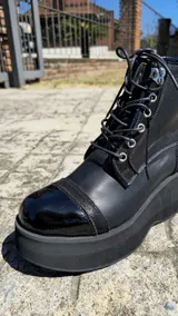 Borcegos de cuero tostado con plataforma bicolor, puntera y talón negros, detalles en animal print y cordones oscuros.