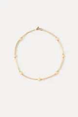 Gargantilla de metal dorado compuesta por una cadena de eslabones tubulares alternados con esferas lisas, con cierre de mosquetón ajustable.