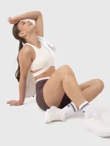 Top deportivo blanco con escote redondo y bandas elásticas cruzadas bajo el busto, con abertura en la espalda.