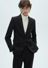 Blazer negro de corte entallado con hombros estructurados, cuello de pico con solapas de muesca, cierre delantero de un botón y bolsillos con solapa.