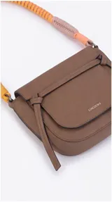 Cartera tipo bandolera negra de formato compacto, con solapa frontal, líneas curvas y correa de hombro tejida multicolor en tonos turquesa y fucsia.