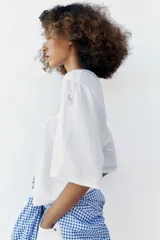 Top de cuello redondo y mangas cortas en forma de capa, color blanco, con detalles de bordados perforados combinados a tono en la parte superior.