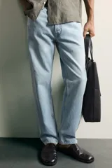Jeans regular fit de mezclilla negra con efecto lavado, corte recto y tiro medio. Cuenta con diseño de cinco bolsillos y cierre frontal con cremallera y botón.