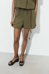Bermuda de tiro alto en color verde militar, con cintura elástica y detalle de cinturón fino trenzado con abalorios decorativos.
