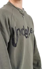 Crewneck de rústico piqué color verde militar con estampado en el frente y la espalda. Mangas ranglan.