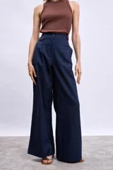 Pantalon de vestir de corte recto y tiro alto, confeccionado en tela de lino en color beige. Presenta pinzas frontales, cierre con botón y detalle de vivos en contraste en la cintura.