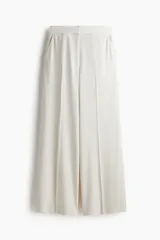 Pantalón de tiro alto con piernas amplias y corte recto. Presenta cierre frontal con botón oculto, bolsillos laterales al bies y bolsillos traseros insertados, con pliegues marcados en la parte delantera y trasera.