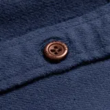 Camisa de franela azul con diseño a cuadros blancos, de manga larga, con cuello clásico, cierre frontal con botones, dos bolsillos con solapa abotonada en el pecho y corte recto.