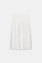 Falda midi blanca de tiro alto con pliegues verticales que le dan volumen y movimiento.