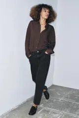 Jeans de tiro medio con corte slim leg, confeccionados en denim color beige. Presentan cintura con trabillas, diseño clásico de cinco bolsillos y cierre frontal con cremallera y botón metálico.