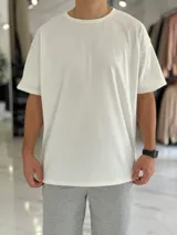 Remera blanca oversize de manga corta, con diseño texturado de líneas finas verticales y cuello redondo.