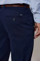 Pantalón de vestir color beige, confeccionado en algodón con spandex. Corte recto, con bolsillos laterales y traseros. Se ajusta a la cintura con cinturón de cuero trenzado en tonos azul y beige.