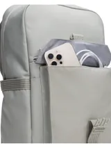 Mochila Under Armour de diseño funcional, confeccionada en poliéster resistente con tecnología UA Storm repelente al agua. Presenta un compartimento principal amplio con espacio acolchado para portátil, bolsillo frontal con cierre y solapa con hebilla ajustable, y bolsillos laterales. Incluye correas ergonómicas ajustables y placa de silicona con el logo de la marca.