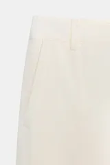 Pantalón capri color verde oliva, de tiro medio, confeccionado en mezcla de lino. Presenta bolsillos laterales y traseros, y cierre frontal con cremallera y botón.