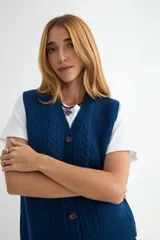 Chaleco tejido de punto color bordó, con escote en V, cierre frontal con botones y diseño de trenzas verticales. Cuenta con dos bolsillos frontales y terminaciones acanaladas.