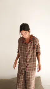 Conjunto de pijama a cuadros con ribetes en color lila, compuesto por camisa de manga larga con botones y pantalón largo.