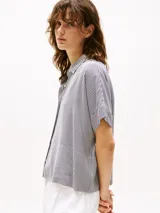 Camisa de manga corta con cuello clásico y cierre frontal con botones. Diseño a rayas verticales en blanco y negro.