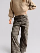 Pantalón sastrero de corte recto y tiro medio-alto, con estampado de cuadros en tonos grises y marrones. Presenta una cintura elástica que aporta comodidad y una textura de tela abrigada.