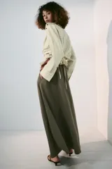 Falda midi tipo capa de tiro medio, confeccionada en mezcla de algodón color verde militar. Cuenta con cintura con trabillas, bolsillos de vivo en los laterales, cierre lateral con cremallera oculta y aplicación de cinturón marrón de estilo western con hebilla metálica grabada.