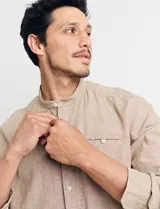 Camisa de cuello mao y manga larga, confeccionada en una mezcla de lino y algodón. Presenta un diseño de corte recto con botones en tono natural y un bolsillo pequeño en el pecho.