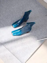 Bota de caña media en cuero negro con punta cuadrada y taco de madera. Cuenta con una costura bordada en color contrastante en el empeine y cierre en la parte trasera.