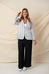 Blazer blanco con rayas verticales negras, confeccionado en algodón y lino. Tiene tres bolsillos y cierre con botón de nácar.