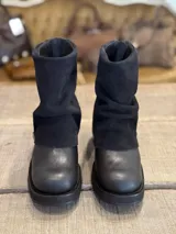 Botas de caña media combinadas en cuero liso y gamuza negra, con diseño de solapa superior y detalle de tira con hebilla metálica lateral.
