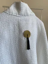 Ruana de diseño estructurado confeccionada en tela tipo tapiz con textura cuadriculada, de corte amplio y caída fluida.