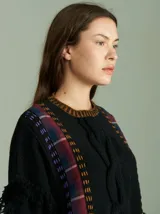 Sweater azul con bordado central en forma de trenza, detalles laterales a cuadros y terminaciones desflecadas. Tiene corte oversize, cuello redondo y tajos laterales con cordones.