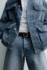 Parka de denim de algodón con efecto lavado, de color azul medio. Presenta cuello solapa, manga larga con puño abotonado, cierre frontal de botonadura oculta y cintura ajustable con cordón interior. Posee cuatro bolsillos utility de plastrón con solapa: dos en el pecho y dos en la cadera.