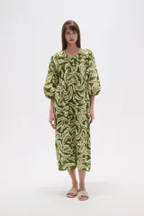 Vestido midi holgado con estampado de hojas en tonos verde y beige, cuello redondo con abertura en V y botones, y mangas 3/4 abullonadas.