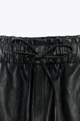 Pantalón tobillero de tiro medio color marrón oscuro, con cintura elástica ajustable con cordón y herretes dorados. Incluye bolsillos delanteros y bolsillos de plastrón en la espalda.