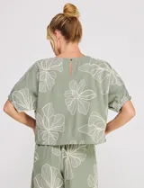 Blusa corta de lino y viscosa color beige, con bordado de grandes flores al tono, cuello redondo, mangas cortas abullonadas y corte holgado.