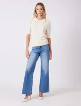 Buzo tejido color beige, marca Nanette, con cuello a la base y solapa decorada con apliques de perlas. Tiene manga corta con puño y ruedo acanalado.